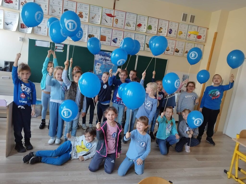 Uczniowie z niebieskimi balonikami.