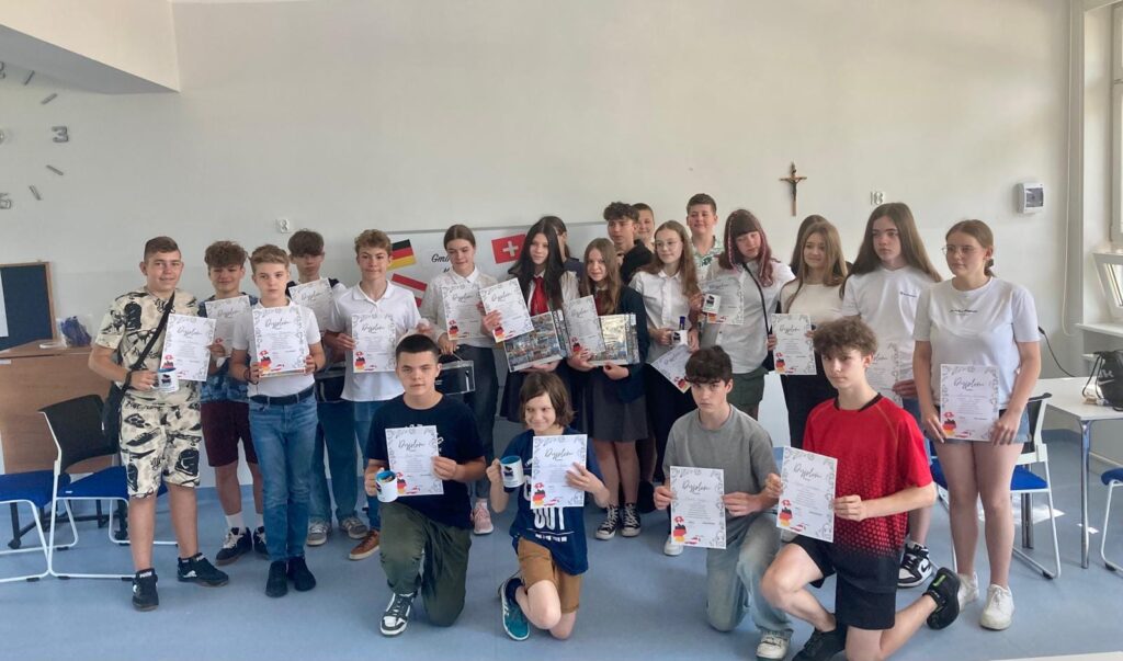 Uczniowie stoją z dyplomami