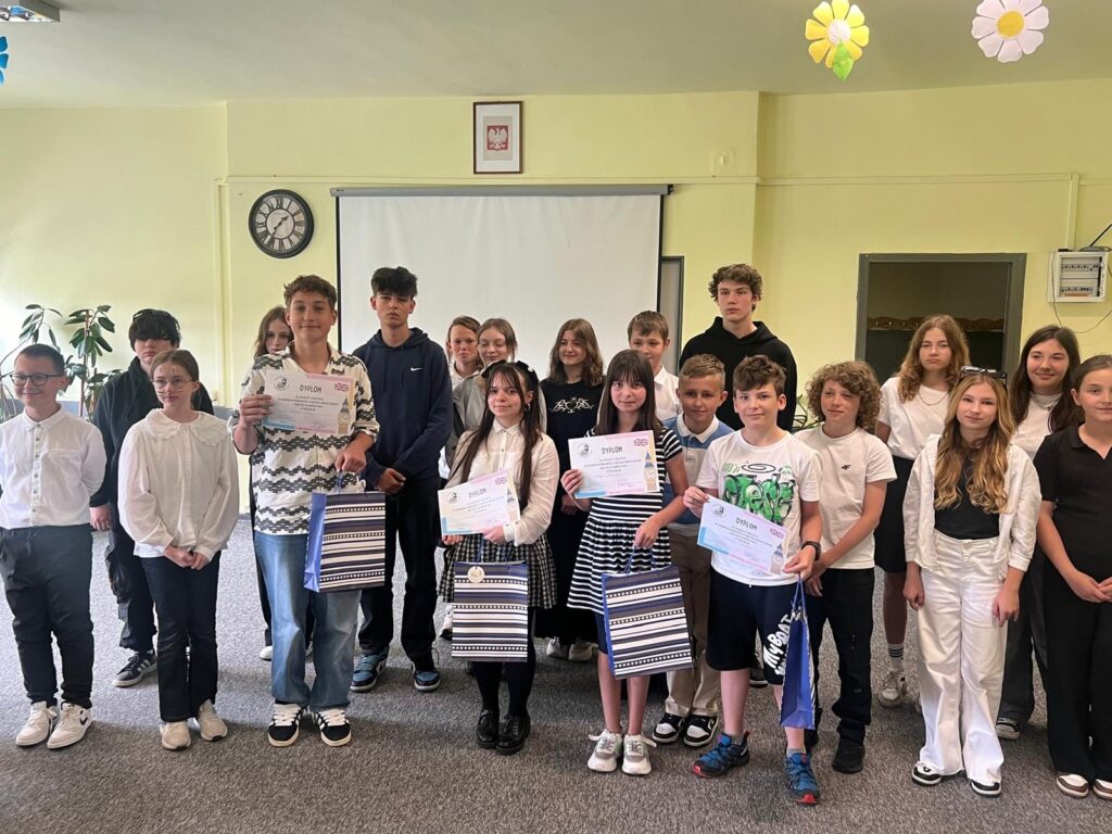 Uczniowie stoją z dyplomami