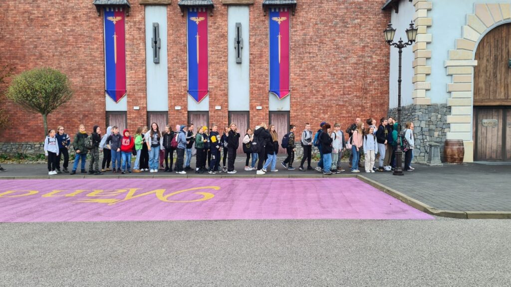 Uczniowie stoją przed parkiem rozrywki