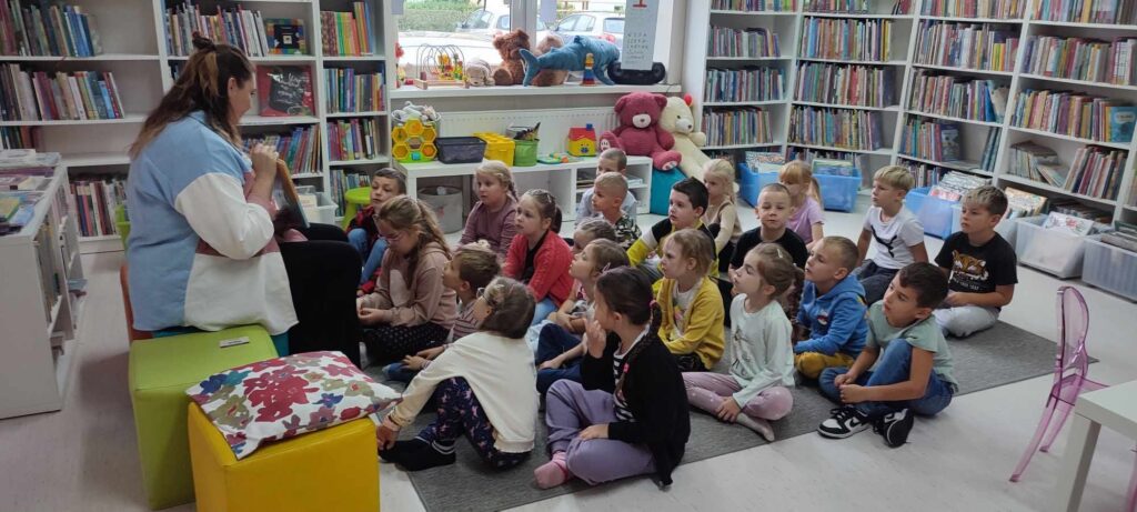 dzieci słuchają bajek czytanych przez bibliotekarkę